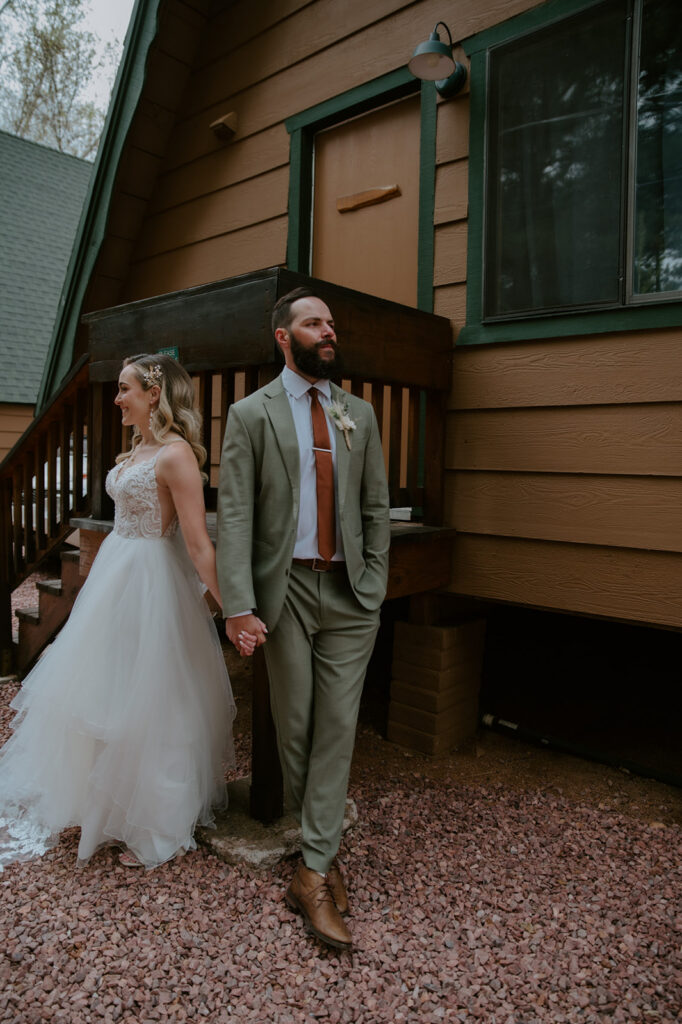 Groomsmen raising beer cans for a celebratory toast while getting ready inside a mountain cabin before the wedding.
