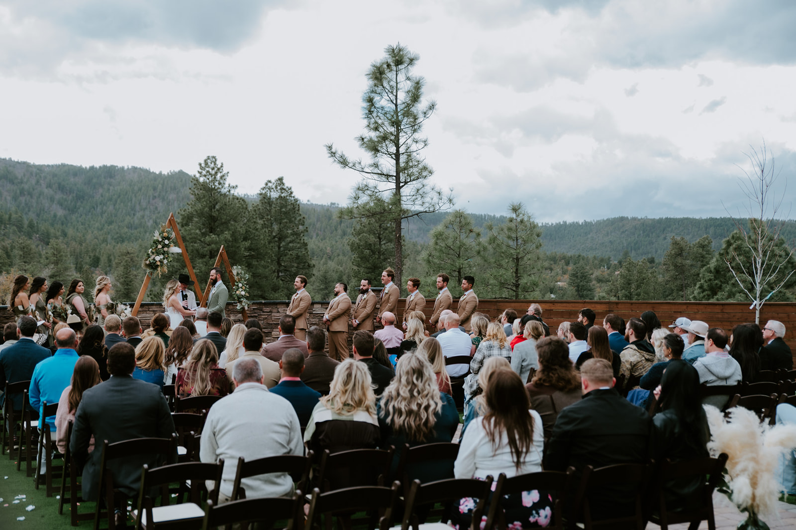 Wide view of an outdoor mountain wedding ceremony with guests gathered at cabins at strawberry hill.
