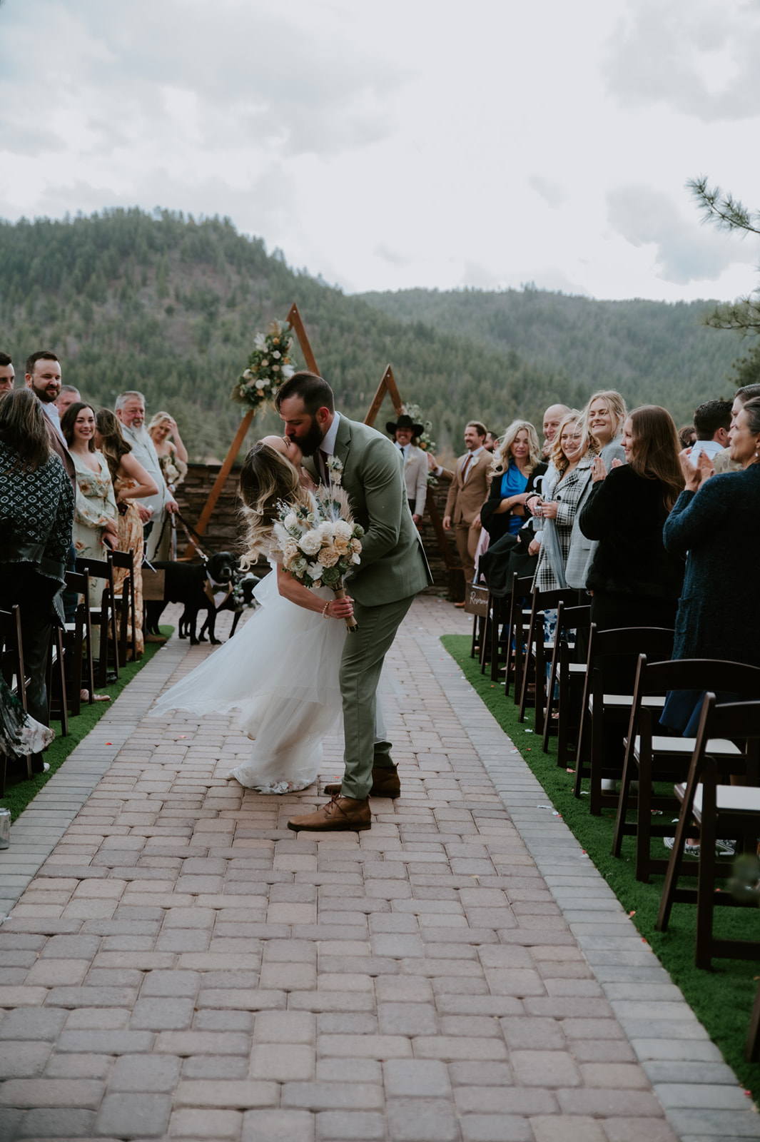 Newlyweds celebrate with a kiss in the ceremony aisle surrounded by cheering guests at cabins at strawberry hill.
