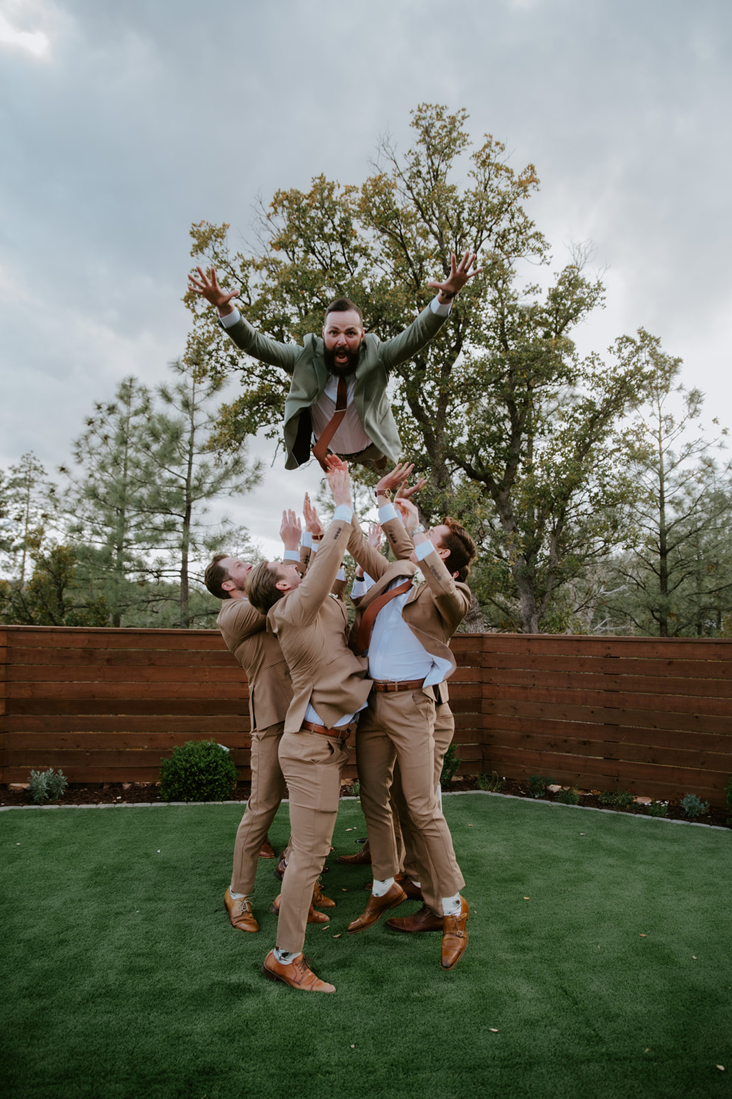 Groomsmen toss the groom into the air during a playful wedding portrait at cabins at strawberry hill.
