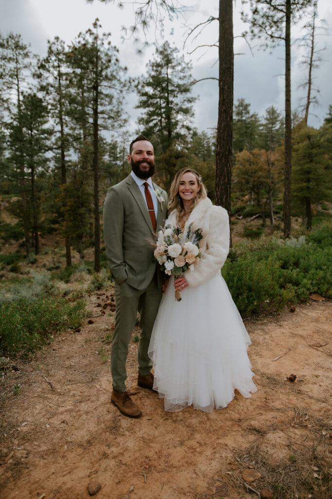 Bride and groom smiling together in the pine forest before their ceremony in Strawberry, Arizona.