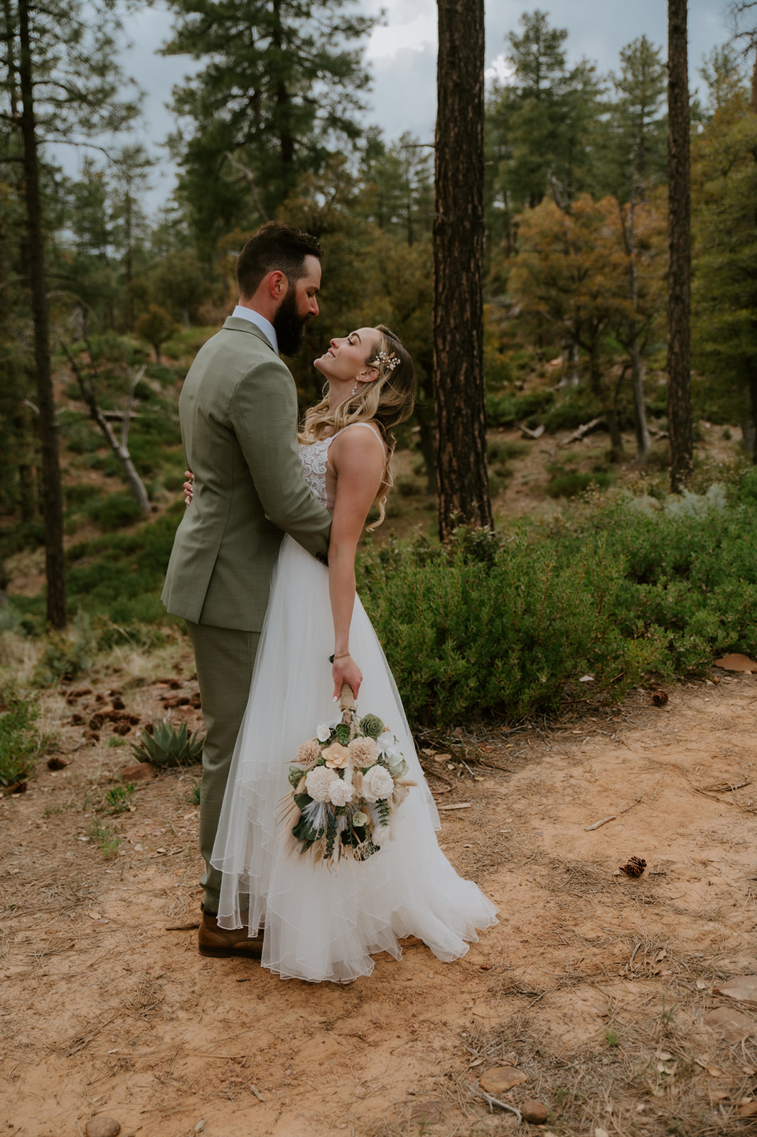 Bride and groom embrace among the pine trees for romantic wedding portraits at cabins at strawberry hill.
