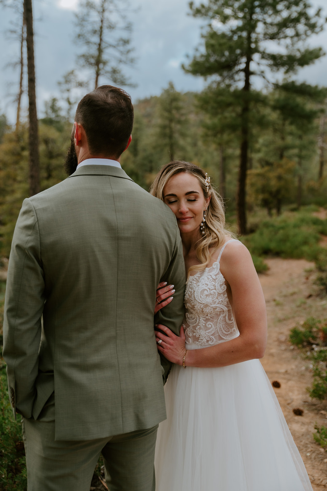 Bride rests her head on the groom's shoulder during a quiet portrait in the forest at cabins at strawberry hill.
