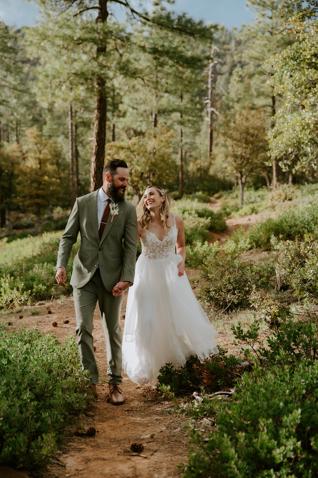 Newlyweds walk hand in hand along a wooded trail at cabins at strawberry hill enjoying their wedding day.
