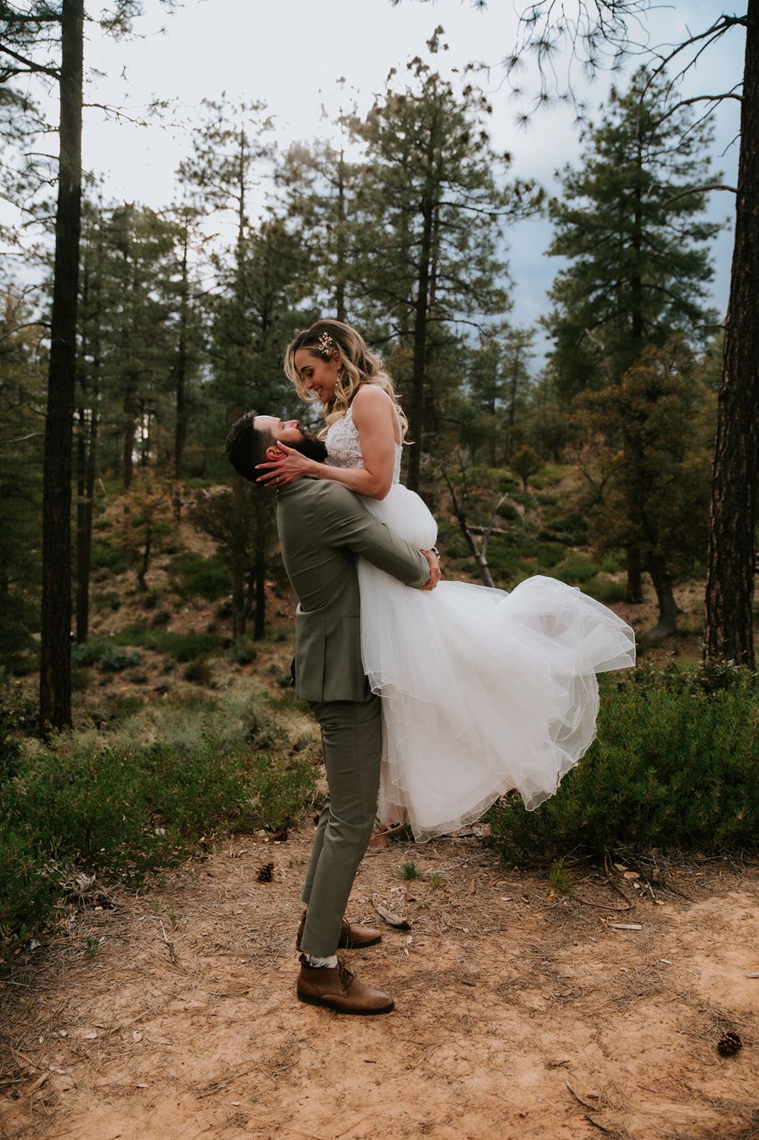 Groom lifts the bride in his arms for a romantic portrait in the pine forest at cabins at strawberry hill.
