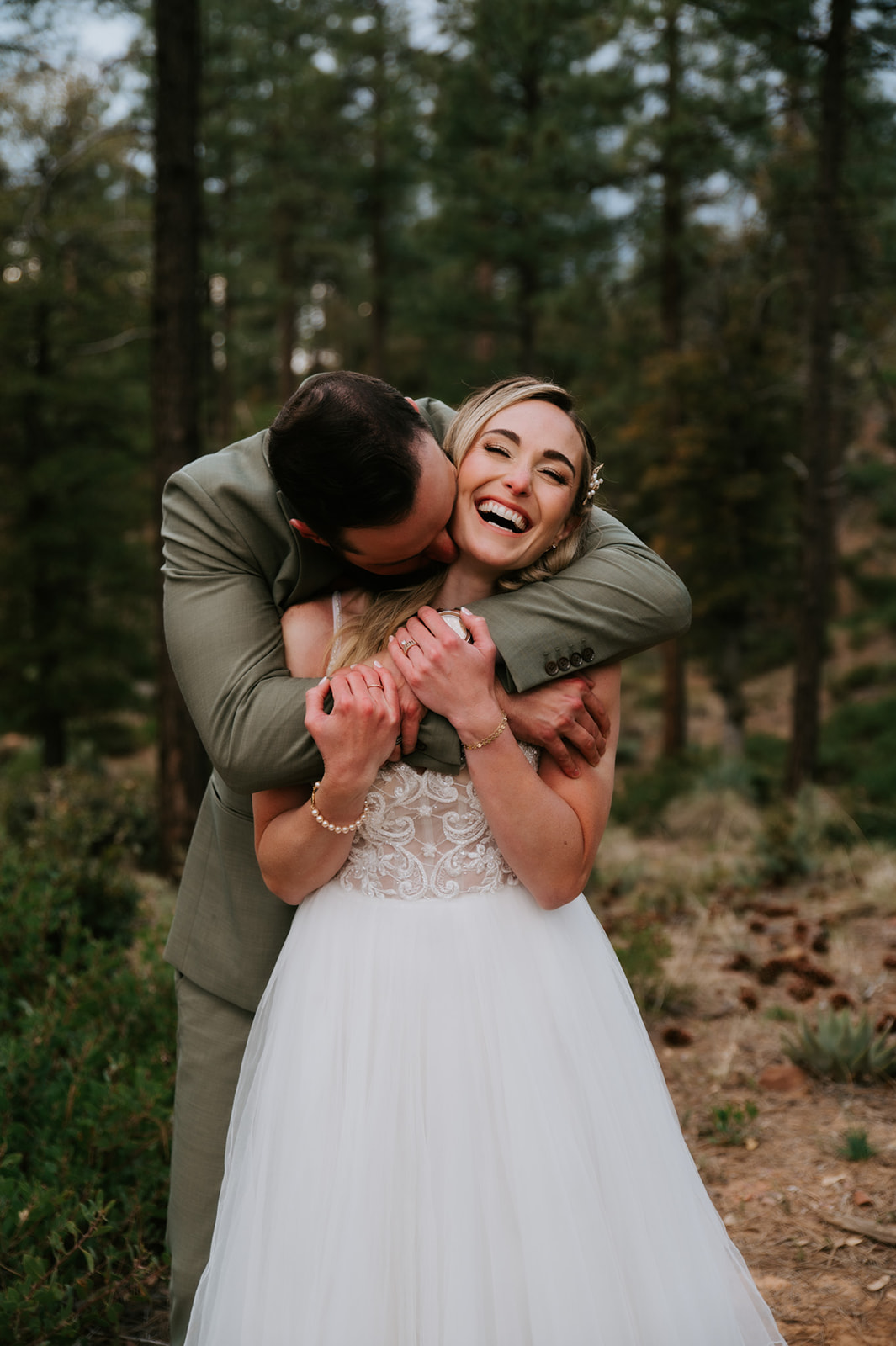 Groom hugs the laughing bride from behind during playful forest wedding portraits at cabins at strawberry hill.
