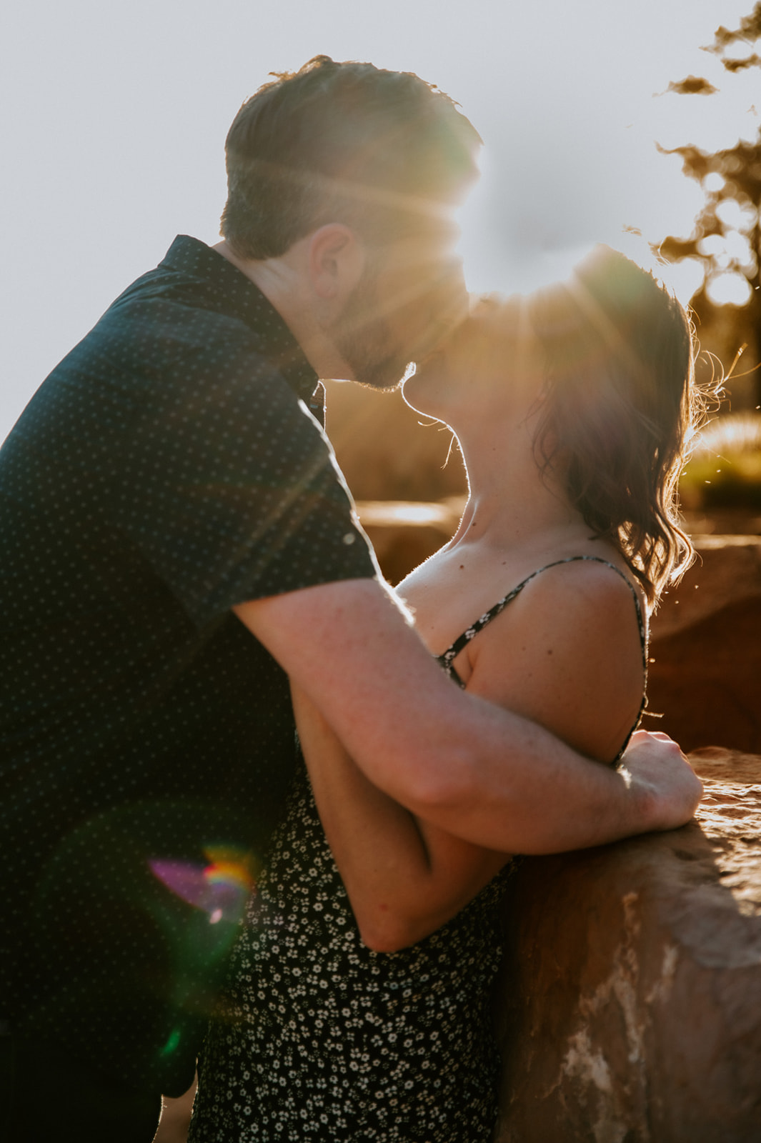Golden hour kiss with sun flare during a Merry Go Round Rock Sedona engagement session.