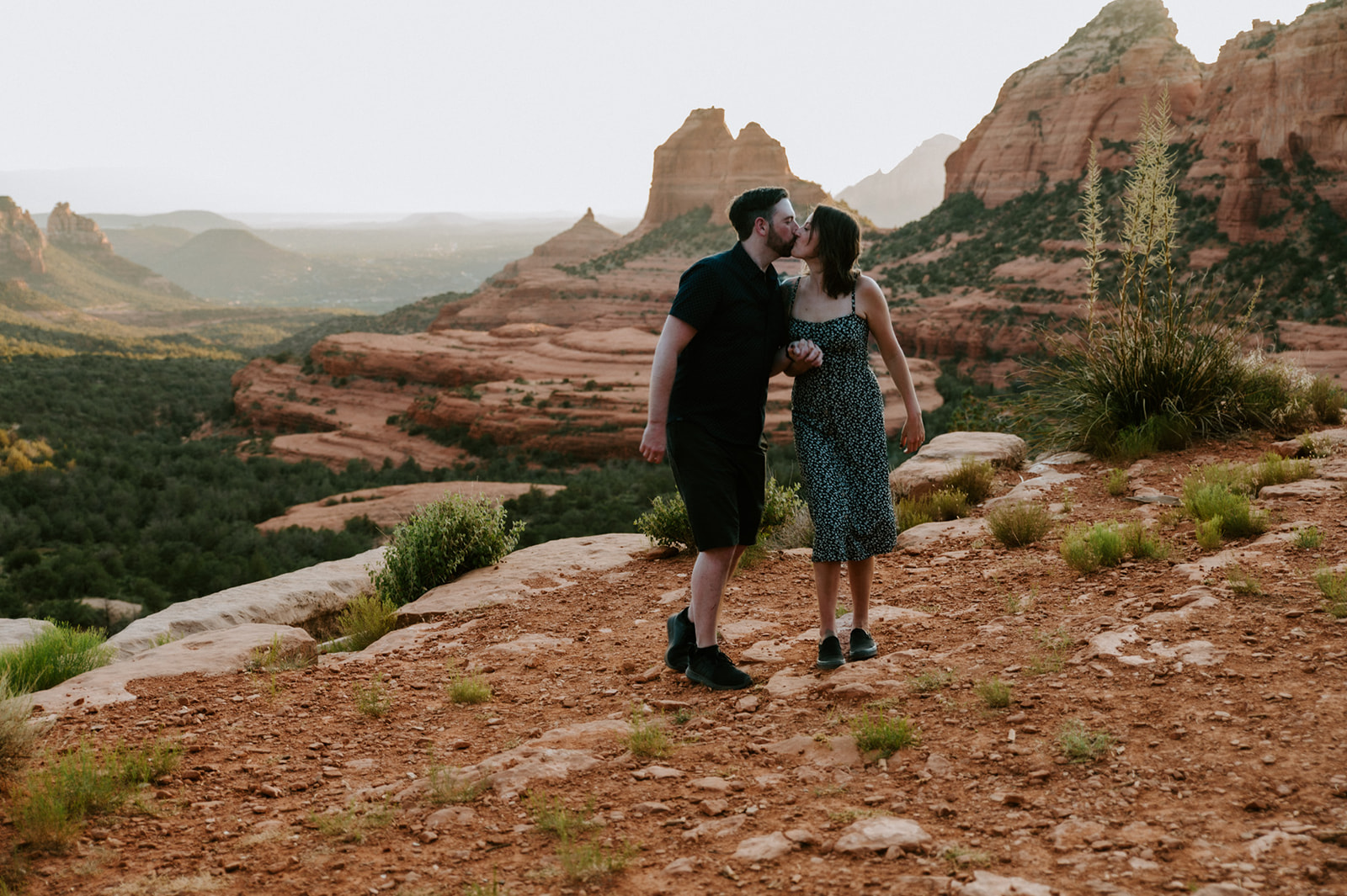 Couple walking hand in hand through the scenic overlook at Merry Go Round Rock Sedona during golden hour.