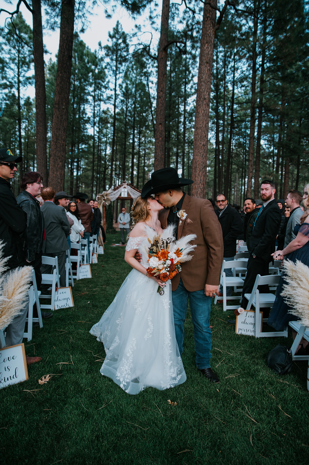 Newlyweds sharing a kiss down the ceremony aisle following their outdoor forest wedding in Pinetop, Arizona.