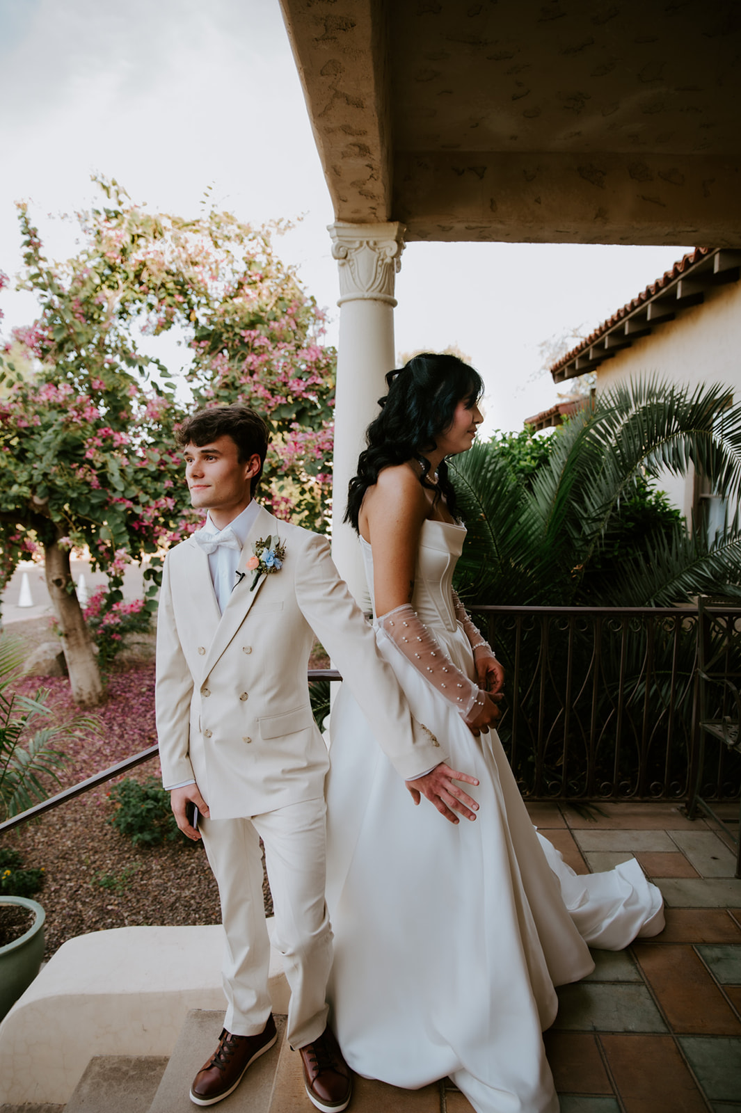 Bride and groom share a first touch without seeing each other before their outdoor wedding ceremony.
