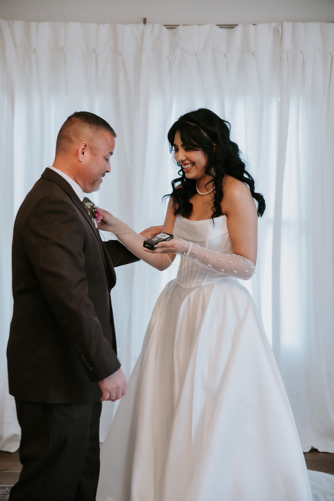 Bride smiles while sharing a special getting-ready moment with a family member before the wedding.
