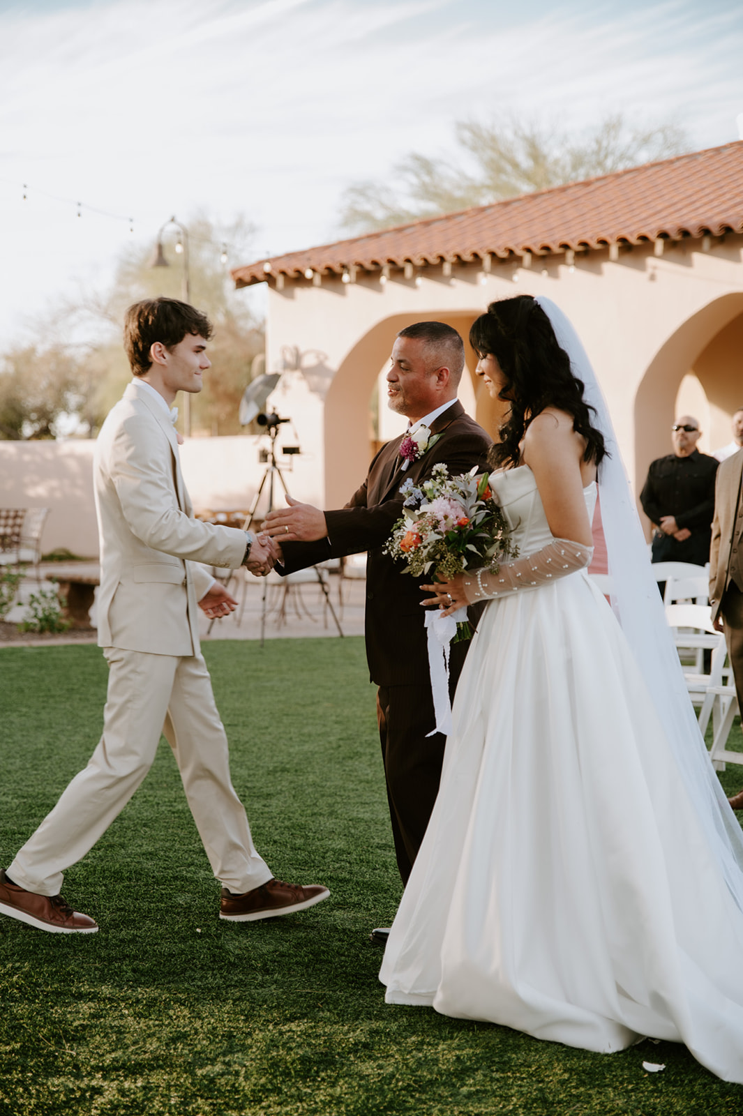 Groom greets the bride and her escort at the start of the outdoor wedding ceremony.
