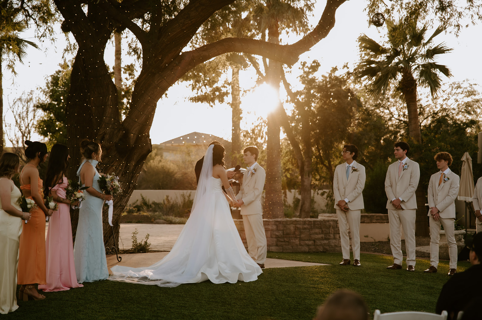 Bride and groom exchange vows beneath a large illuminated tree during a golden-hour ceremony at Secret Garden by Wedgewood Weddings.
