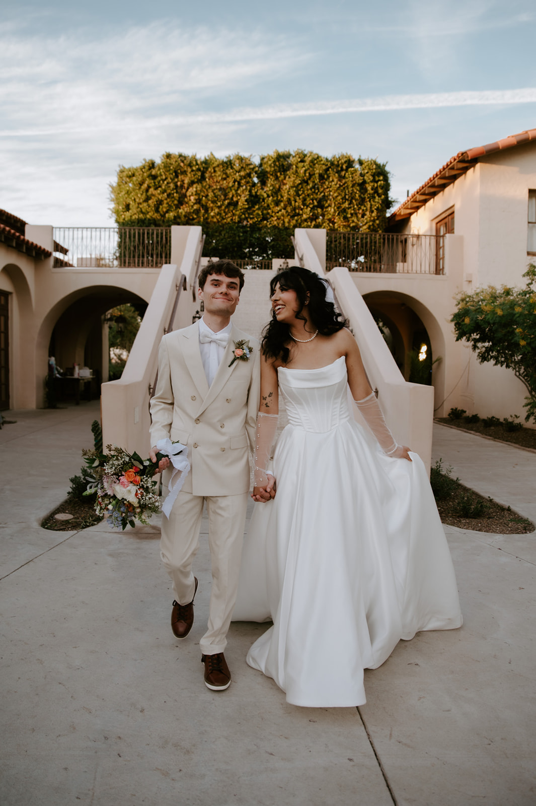 Newlyweds walk hand in hand through the courtyard after their wedding ceremony.
