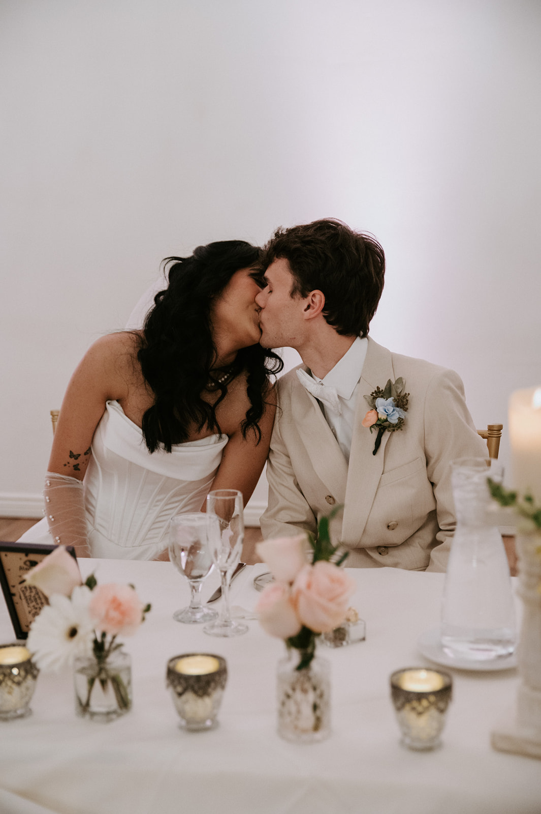 Newlyweds share a kiss at their sweetheart table at Secret Garden by Wedgewood Weddings.
