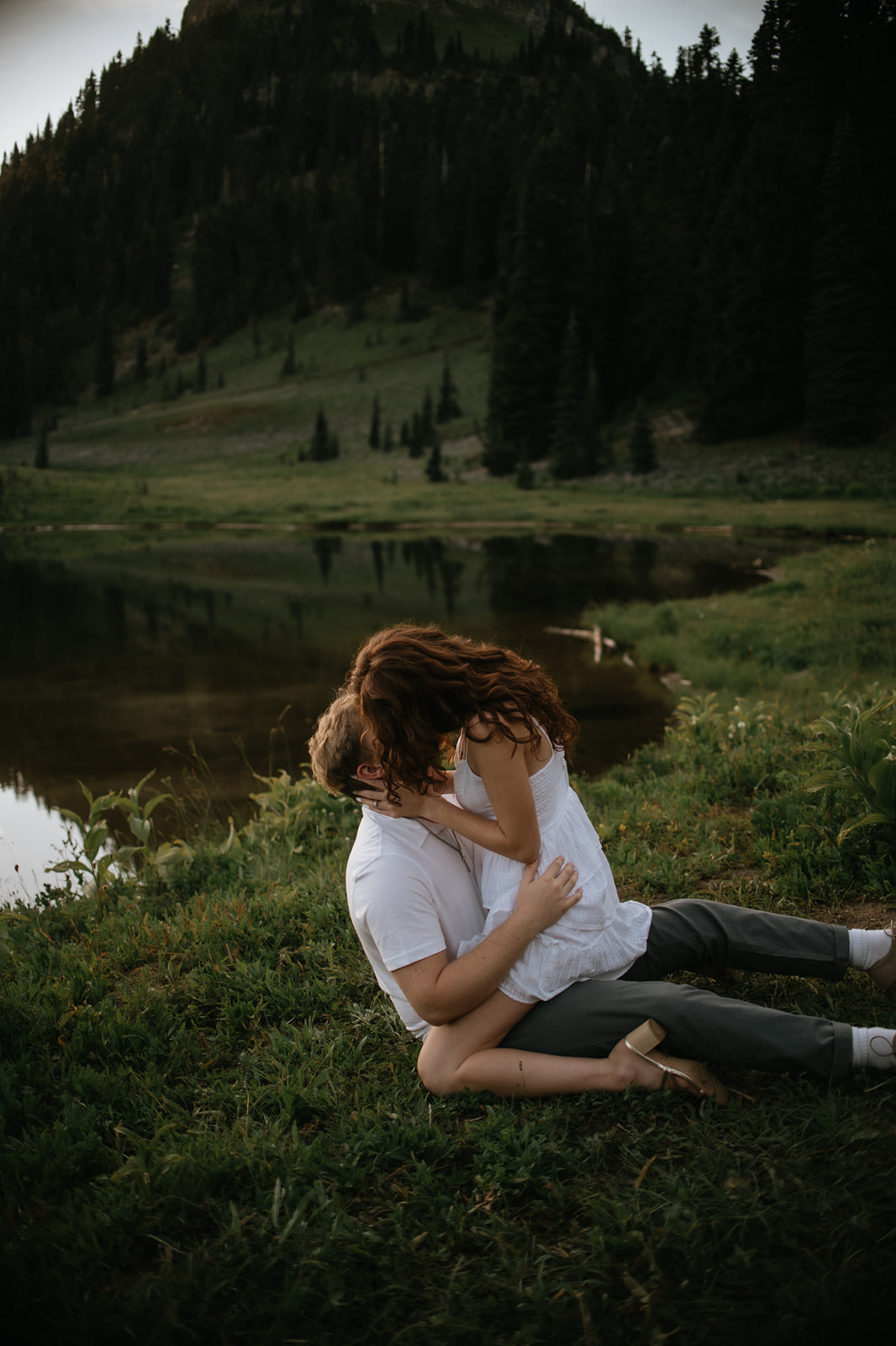 Couple eloping in Washington sharing a playful kiss beside a peaceful alpine lake surrounded by mountain scenery.