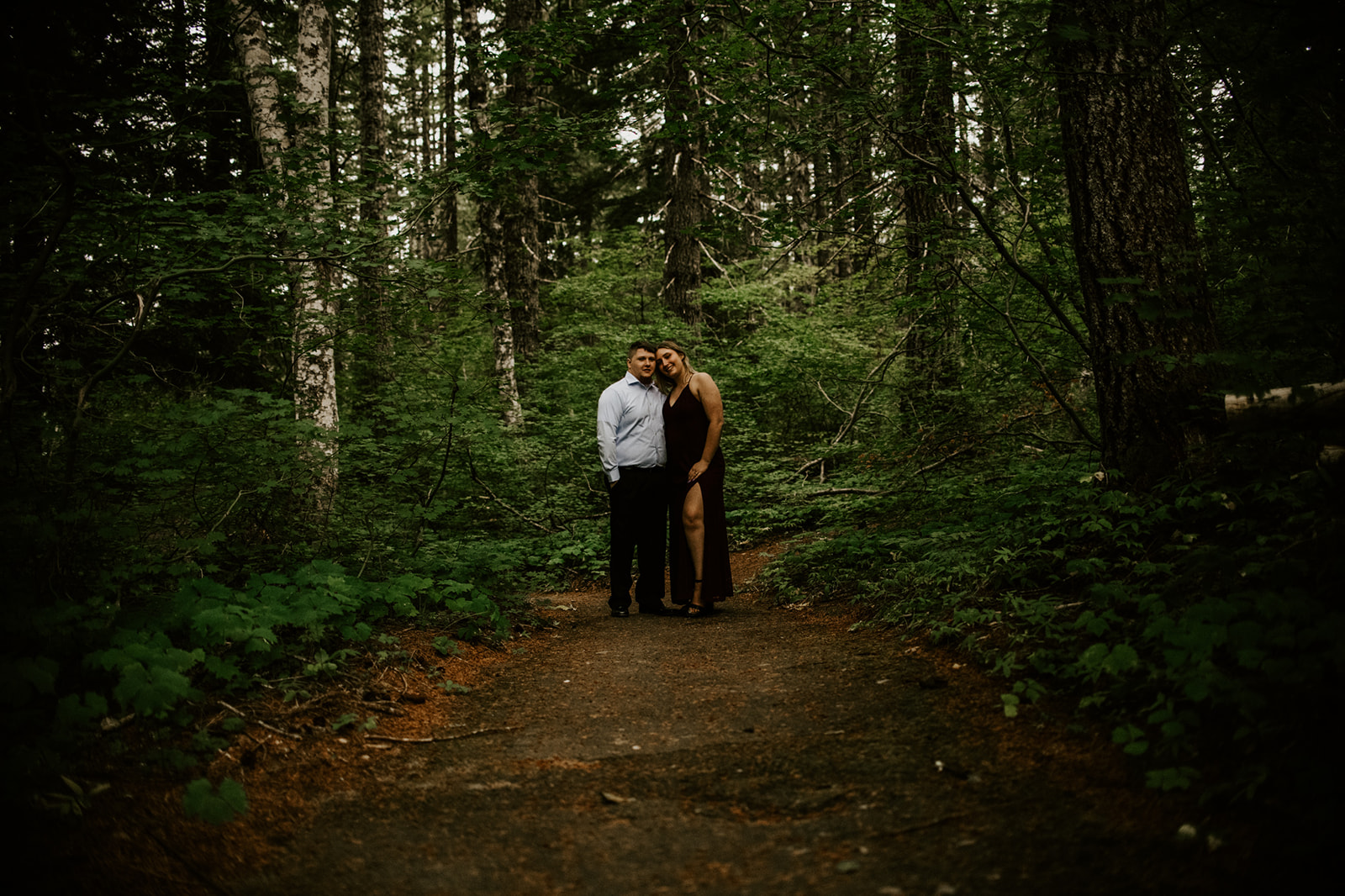Couple eloping in Washington standing together on a quiet trail surrounded by dense evergreen forest.