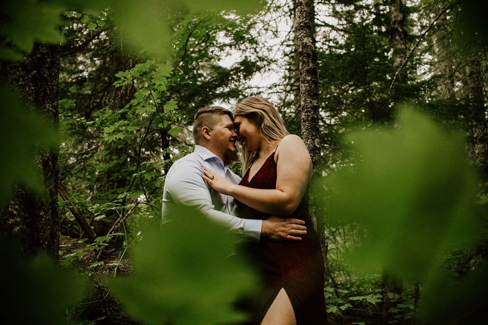 Couple eloping in Washington sharing an intimate moment surrounded by lush green forest and evergreen trees.