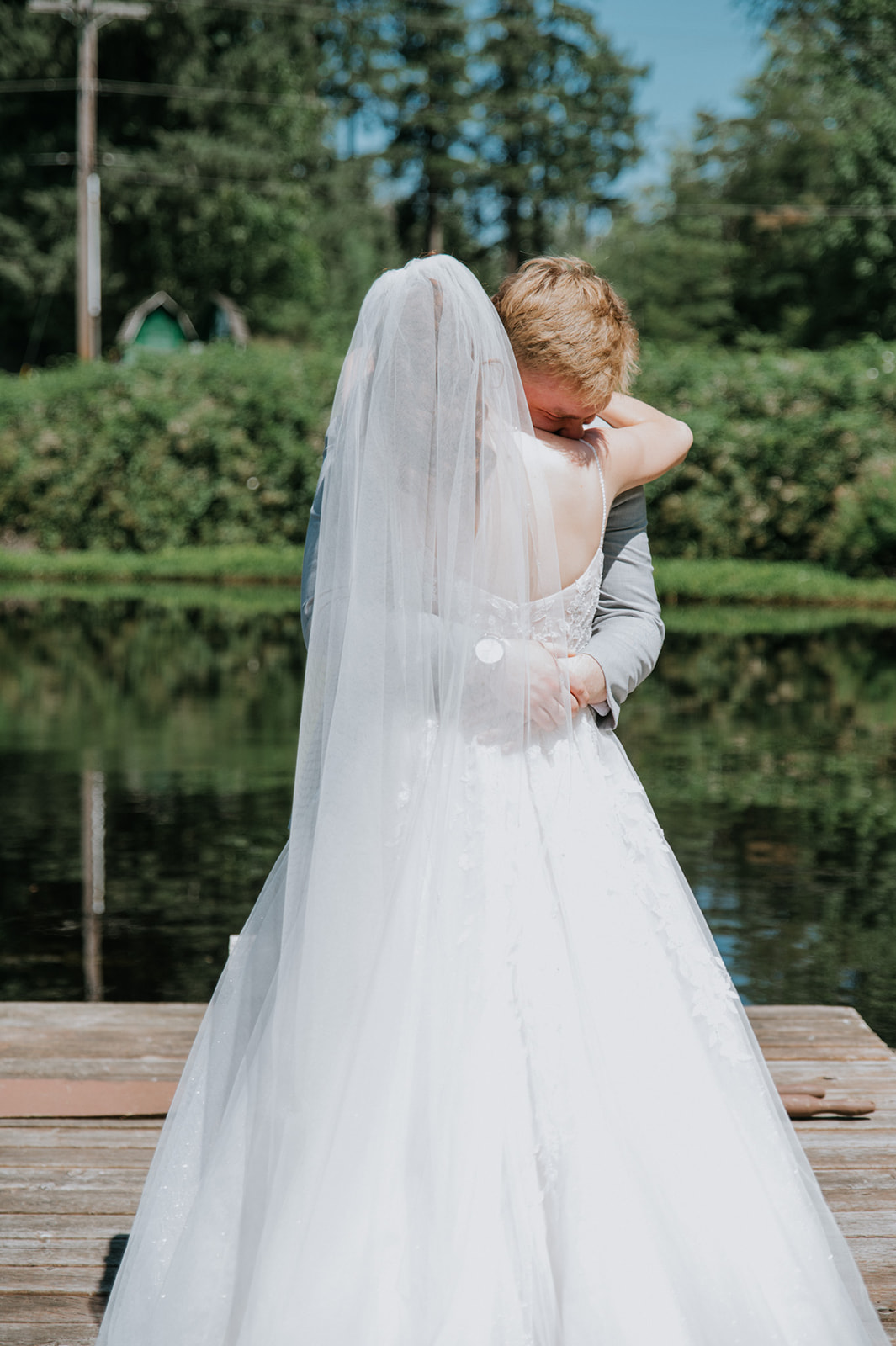 Bride and groom embracing on a wooden dock overlooking a peaceful pond during their wedding in seattle.