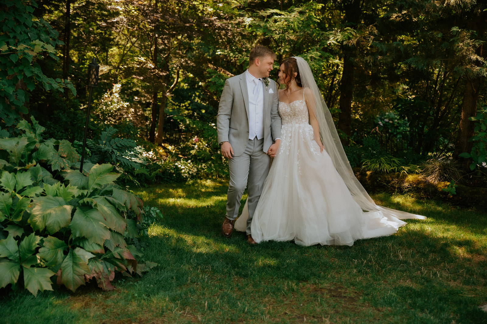 Bride and groom holding hands while walking through a lush green garden during their wedding in seattle.