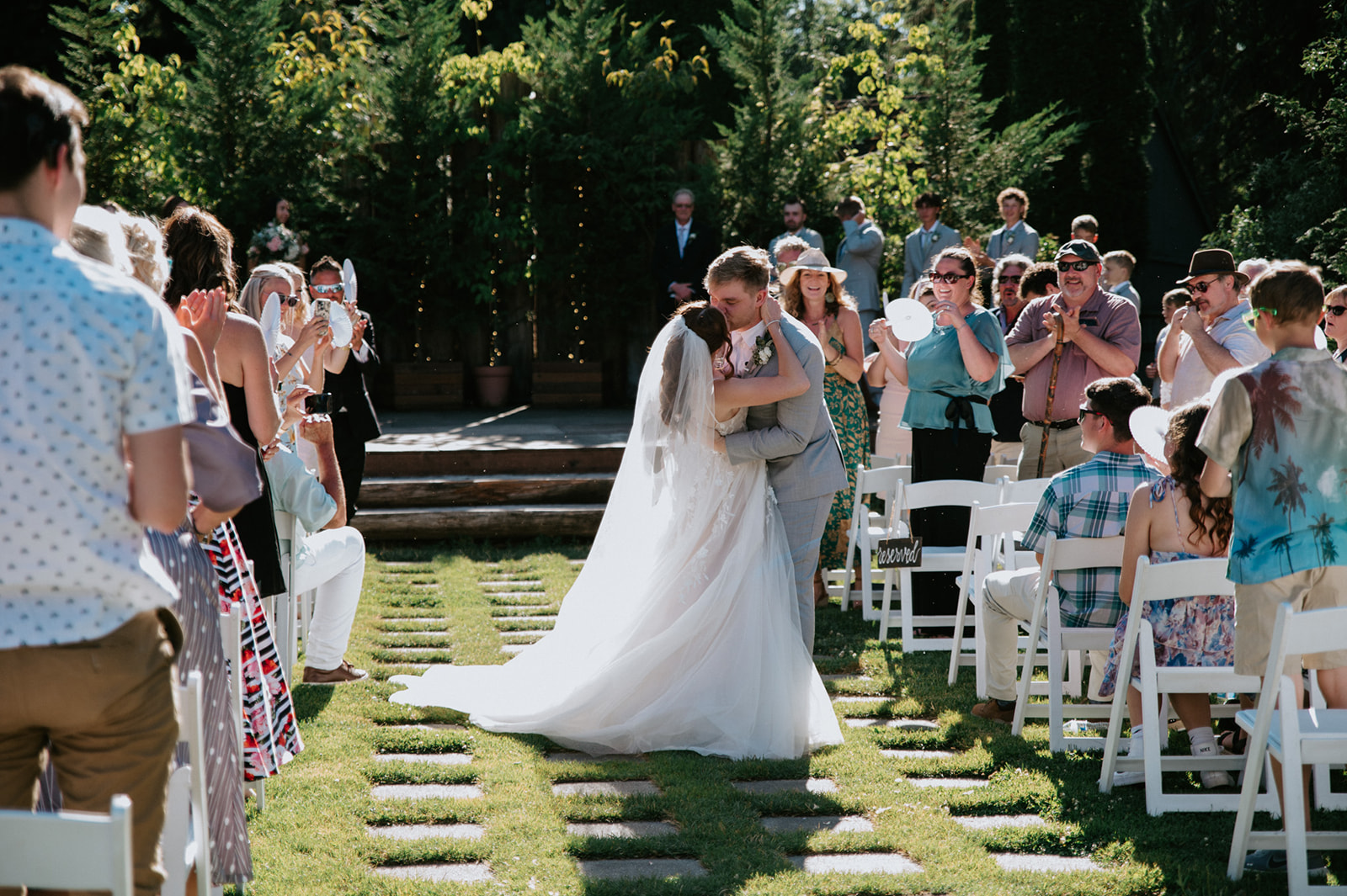 Newlyweds kissing in the ceremony aisle as guests cheer and take photos during their wedding in seattle.