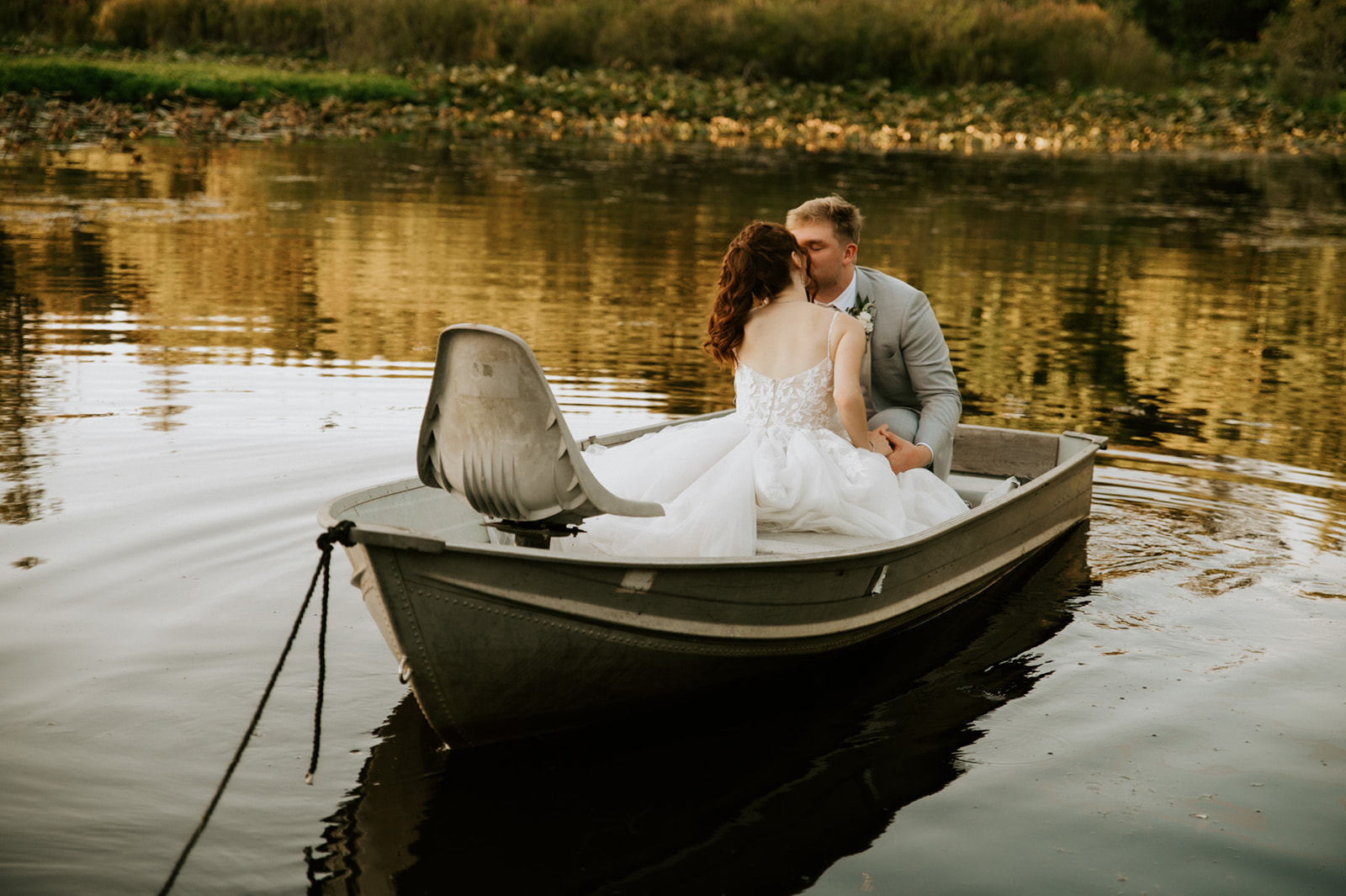 Newlyweds sharing a kiss in a small rowboat on a peaceful pond during their wedding in seattle.